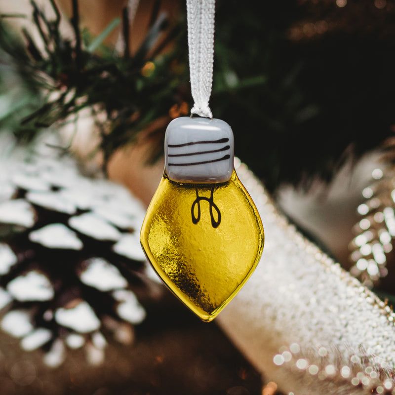 décoration de Noël en forme d'ampoule lumineuse en verre suspendue dans le sapin avec un ruban